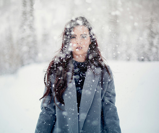 A Woman with long dark hair walks through snowfall