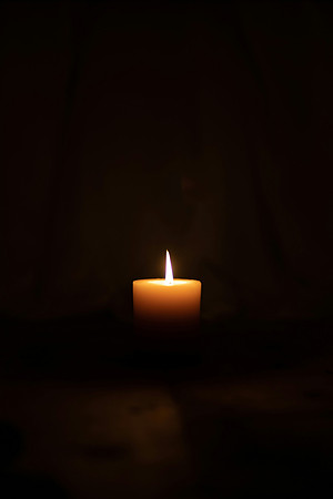 A lone candle burns in the dark