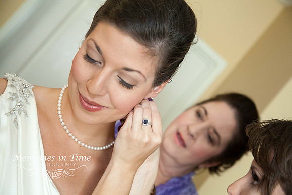 A bride's jewelry is put on by her mother