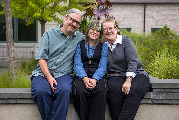 A family of three poses on a wall