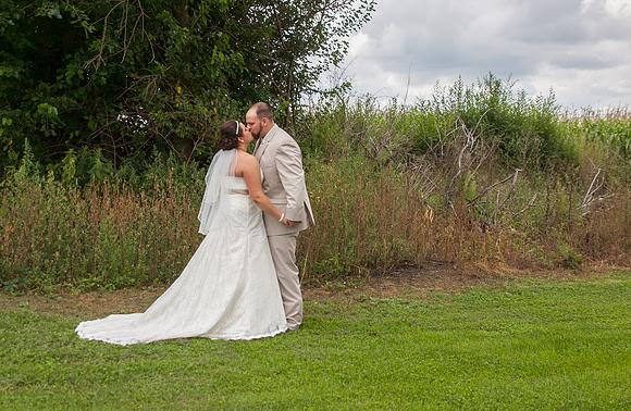 A wedding couple kisses in the family cornfield