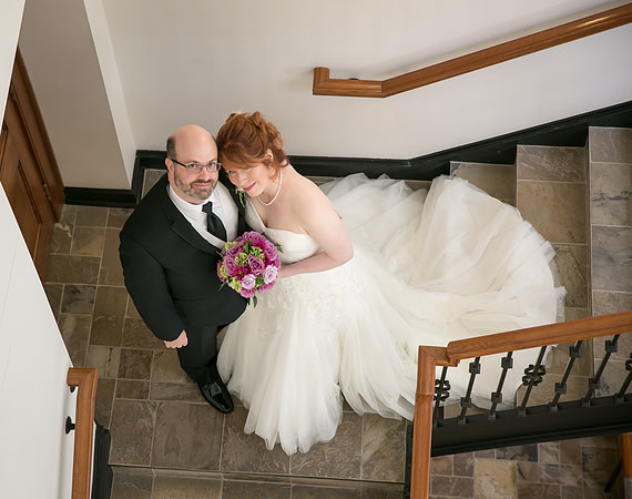 A formal portrait of the Groom and his red-headed bride on hidden stairs at the Minneapolis Club