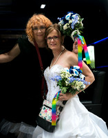 Two brides, one in a black dress, one in a white take a moment getting off the party bus